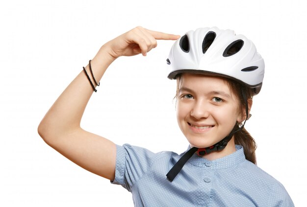 A rapariga em um capacete de bicicleta aponta para um capacete isolado no branco