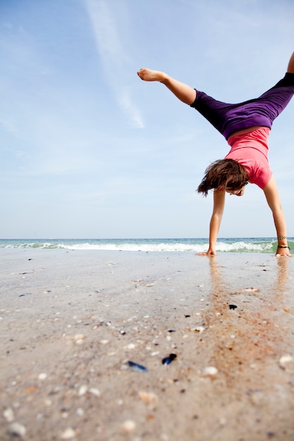 A rapariga mostra um acrobático na praia.