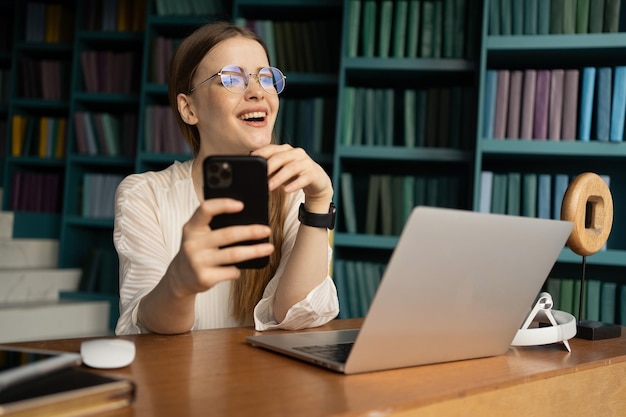 A recepcionista é uma mulher com óculos trabalhando em um escritório moderno usando um laptop