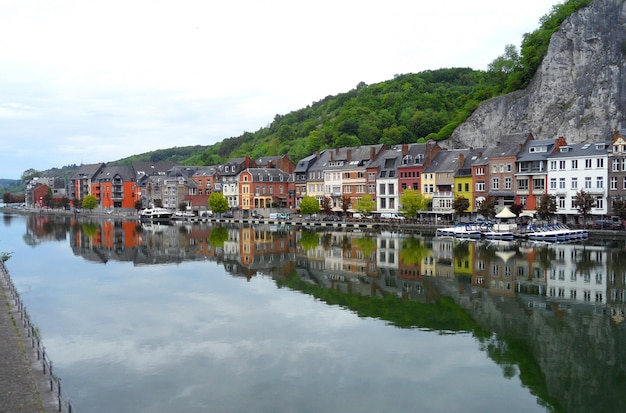 A reflexão de arquiteturas tradicionais coloridas no rio Meuse em Dinant, Bélgica