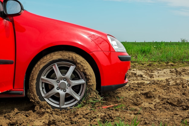 A roda do carro vermelho presa na lama