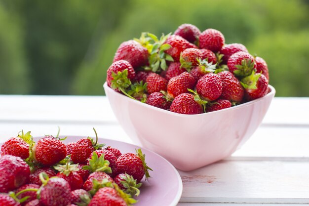 A safra de morango colhida em um prato. Frutos maduros de verão