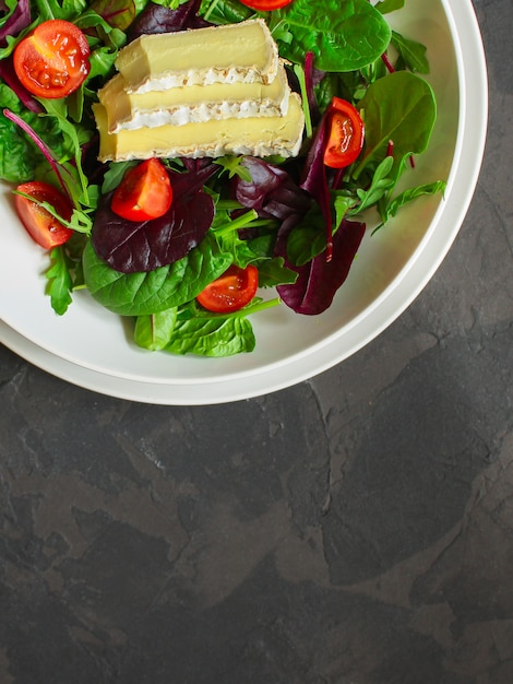 A salada saudável sae em uma placa e em um queijo brancos (os verdes da mistura micro, petisco suculento). fundo de comida