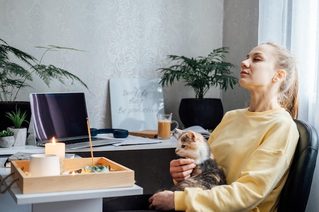 A saúde mental e a vida profissional equilibram a jovem com velas acesas de gato relaxando e descansando