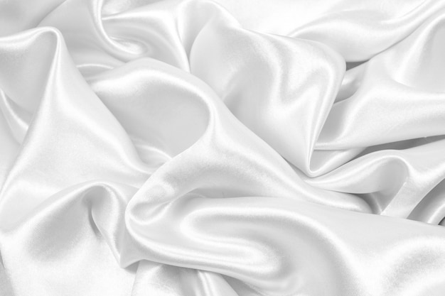 A seda de prata elegante lisa bonita ou a textura do cetim podem usar-se como o fundo abstrato. cor de tecido