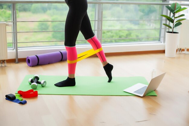 A senhora faz exercícios em casa na frente de um laptop para manter o peso ideal e uma boa forma física.