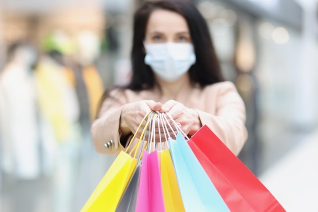 Foto a senhora usa máscara facial e segura um monte de pacotes após o dia inteiro de compras