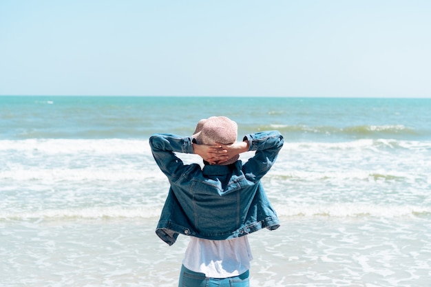 A sensação da mulher relaxa e liberdade que olha a praia com praia azul do skyand.