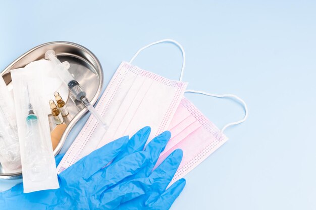 A seringa de injeção com luvas e máscara Seringa com injeção em uma bandeja médica Faça uma vacinação no hospital Suprimentos médicos