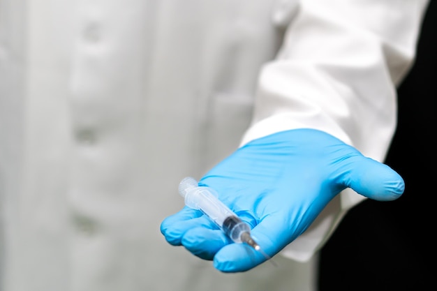 A seringa médica na mão do médico é um close-up Um médico em luvas azuis segura uma seringa com uma vacinação de coronavírus Vacinação obrigatória da população contra covid19