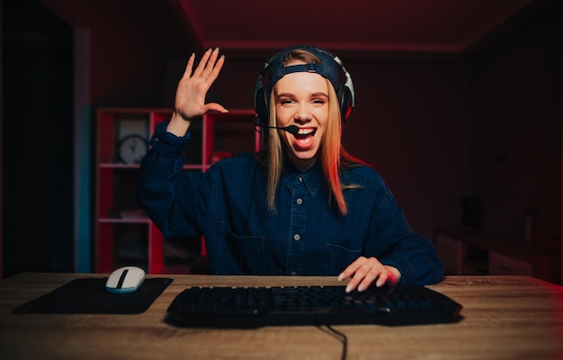 A serpentina feminina positiva se senta à noite na sala do computador e se comunica em um fone de ouvido