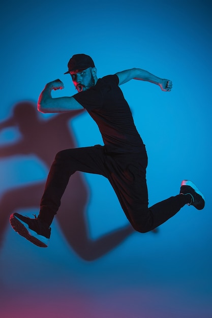 A silhueta de um jovem dançarino de break de hip hop dançando sobre fundo colorido