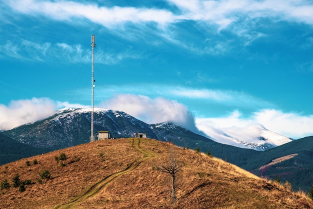 A silhueta de uma torre de telecomunicações contra o pano de fundo de um céu azul incrivelmente bonito com nuvens brancas brilhantes embaçadas