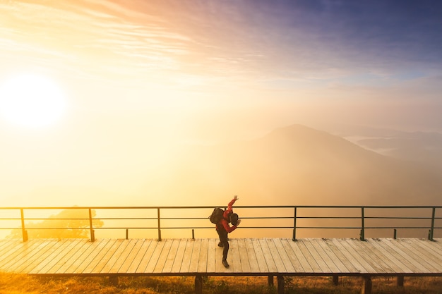 A silhueta do homem levanta as mãos no pico da montanha