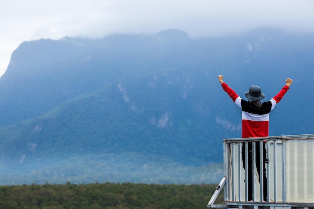 A silhueta do homem levanta as mãos no pico do conceito de sucesso nas montanhas