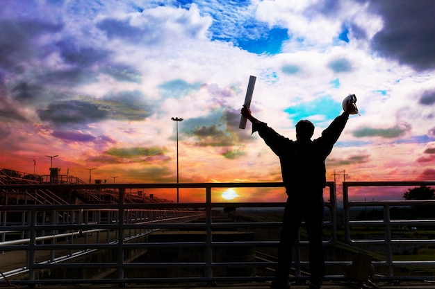 Foto a silhueta masculina de um engenheiro masculino encantado com o horário de check-in ao pôr do sol.