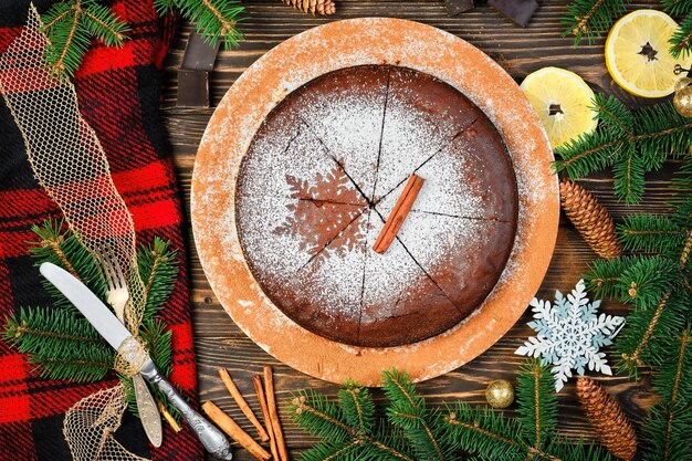 A sobremesa caseira tradicional é bolo de chocolate. Torta de Natal em uma mesa de madeira escura decorada com galhos de uma árvore de Natal. Vista superior da torta sueca pegajosa kladdkaka