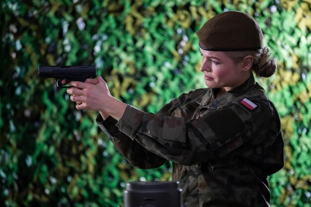 Foto a soldada aponta a pistola para um alvo distante concentrando-se muito enquanto o faz.