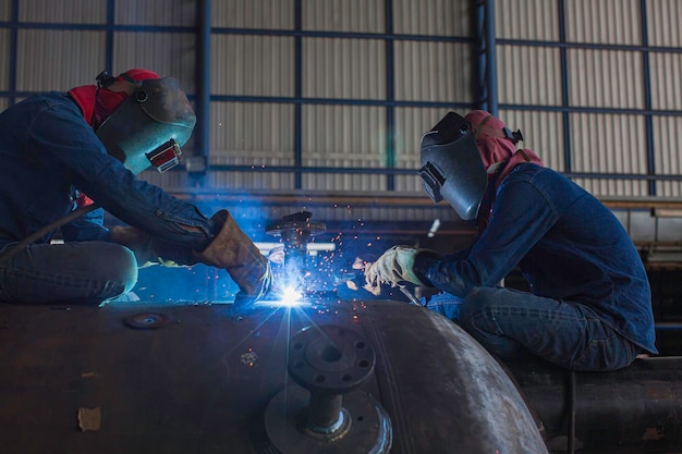 A soldagem de dois trabalhadores masculinos faz parte da construção do tanque de bocal de máquinas