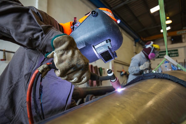 A soldagem de metal de trabalhador masculino faz parte da construção de dutos de maquinário, petróleo e gás