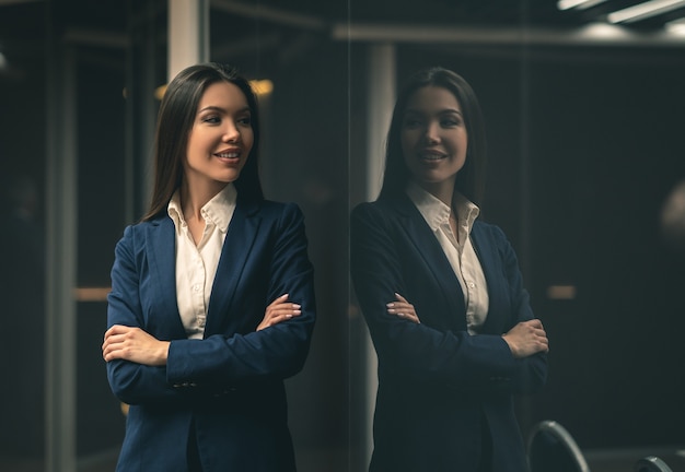 A sorridente empresária asiática em pé dentro de casa