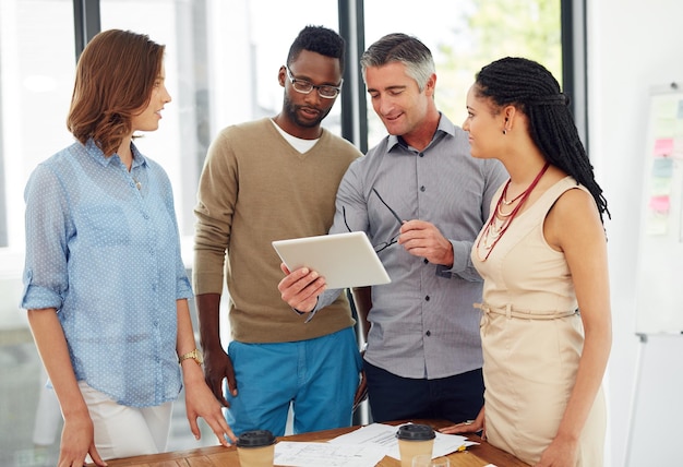 A tecnologia ajuda a apoiar o local de trabalho Foto de um grupo de empresários discutindo algo em um tablet digital