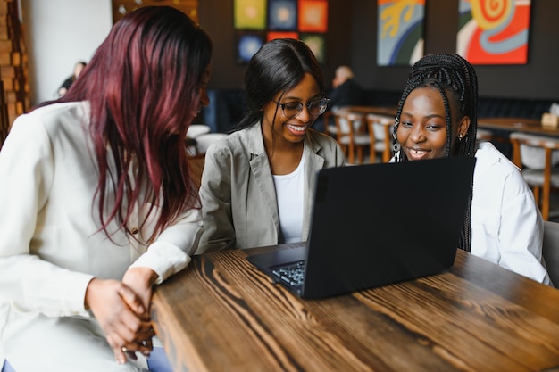 A tecnologia é um recurso fantástico para ferramentas de estudo. Três estudantes no café.