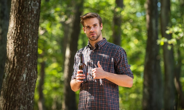 A temporada de acampamento começa ele adora caminhadas turismo conceito de aventura bebendo cerveja no acampamento não deixe lixo na floresta ecologia poluição homem beba cerveja na floresta relaxe no fim de semana de piquenique de verão