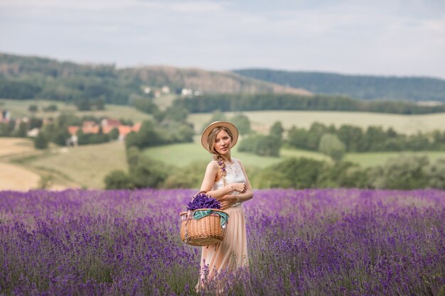 A temporada de verão. Campos de lavanda. Uma garota com uma cesta de campo de lavanda.