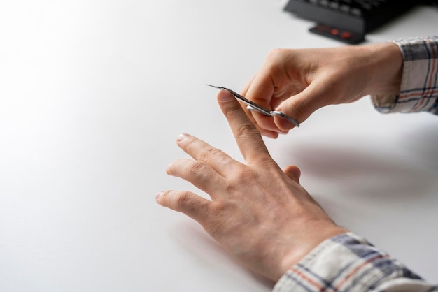 A tesoura de metal segurando e unhas cortadas cuidados de saúde pessoal