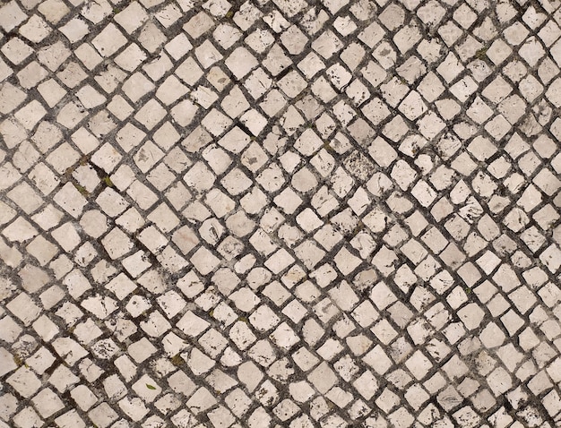 A textura das velhas pedras de pavimentação no chão velha estrada de tijolos brancos