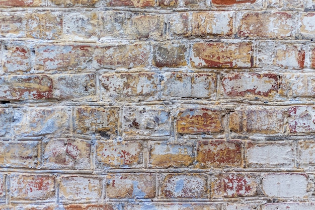 A textura de uma parede de tijolos antigos com vestígios de tinta velha
