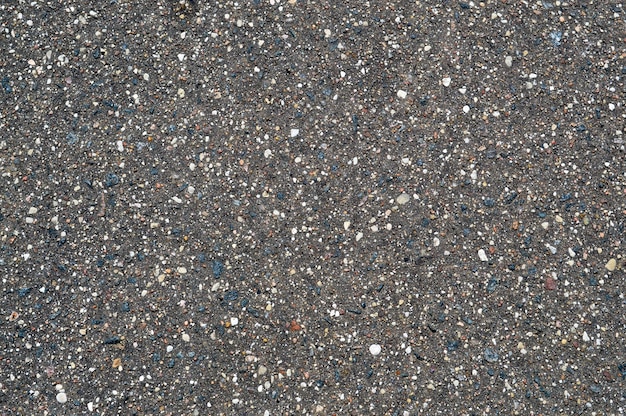 A textura do fundo da estrada asfaltada de pedra preta e cinza com pequenos seixos