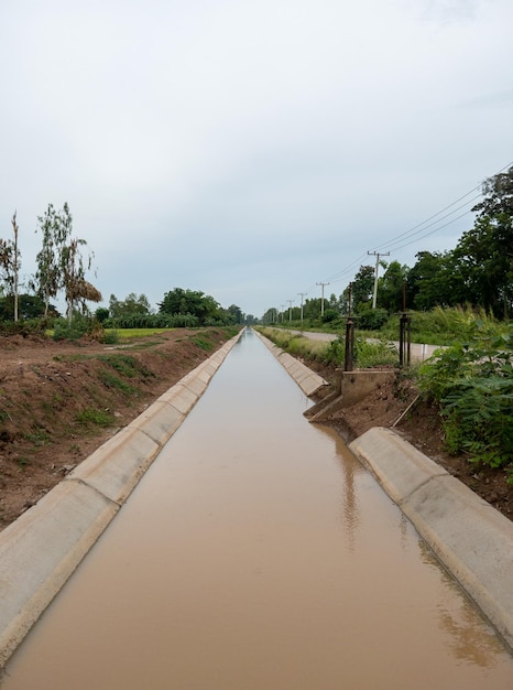 Foto a vala de drenagem de concreto com a porta de água para o sistema de irrigação na área de plantação vista frontal com o espaço de cópia