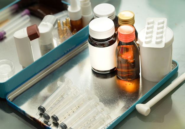 A variedade de pacotes de medicamentos no tacle inclui uma seringa de xarope MDI em spray de garrafa no fundo desfocado