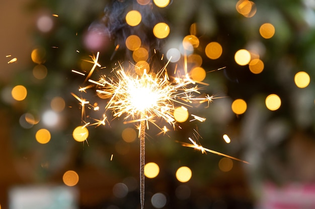 A vela cintilante de Natal queima no fundo da árvore de Natal Decoração de iluminação de Natal em casa interior Festivo Magia acende luzes para festa natalícia véspera de Natal com fogos de artifício