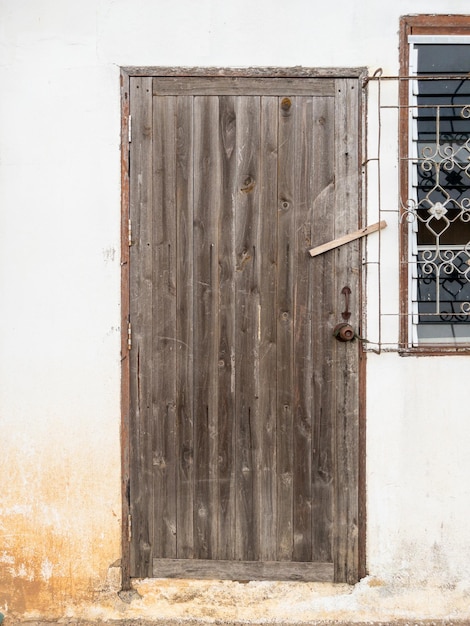 A velha porta de madeira com a fechadura de madeira na parede branca