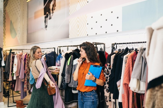 A vendedora ajuda o comprador a escolher entre diferentes roupas.