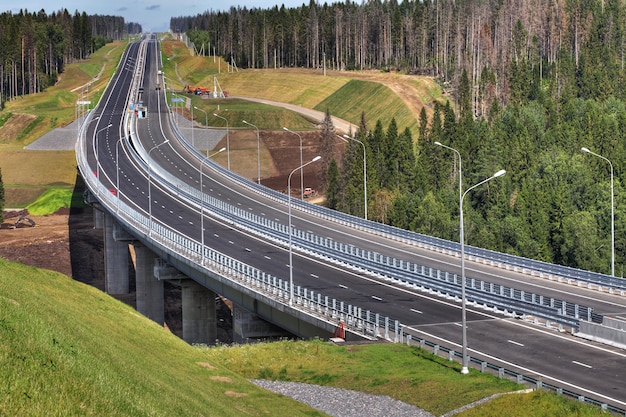 A via expressa atravessa a floresta, ponte de cavalete de aço é suportada por suportes de concreto armado.