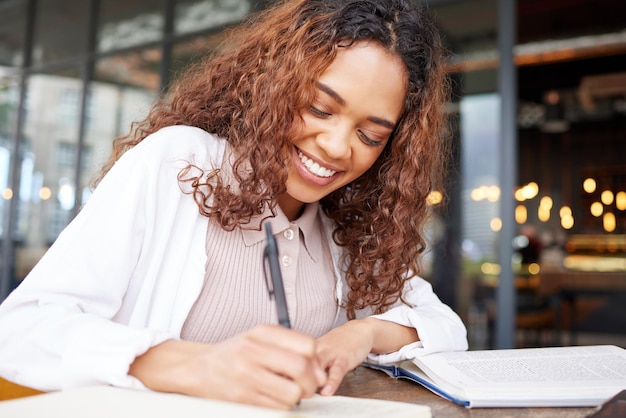 A vida de um estudante foto de uma jovem empresária escrevendo em um caderno enquanto estava em um café