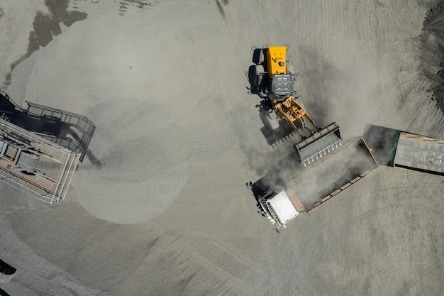 A vista aérea de carregadores de areia está colocando pedras em caminhões basculantes