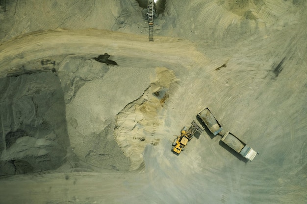 A vista aérea de carregadores de areia está colocando pedras em caminhões basculantes