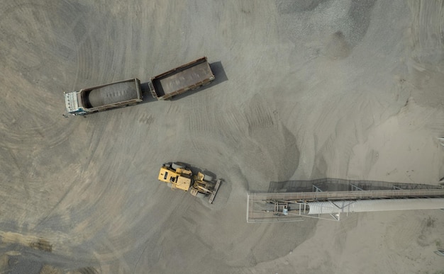 A vista aérea de carregadores de areia está colocando pedras em caminhões basculantes