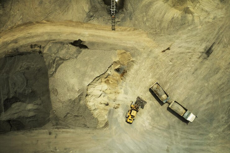 A vista aérea de carregadores de areia está colocando pedras em caminhões basculantes