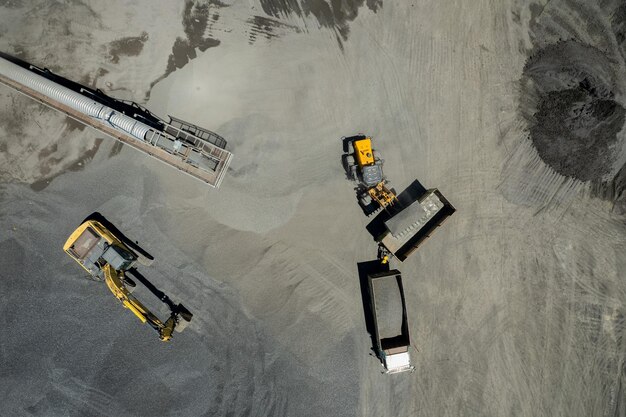 A vista aérea de carregadores de areia está colocando pedras em caminhões basculantes