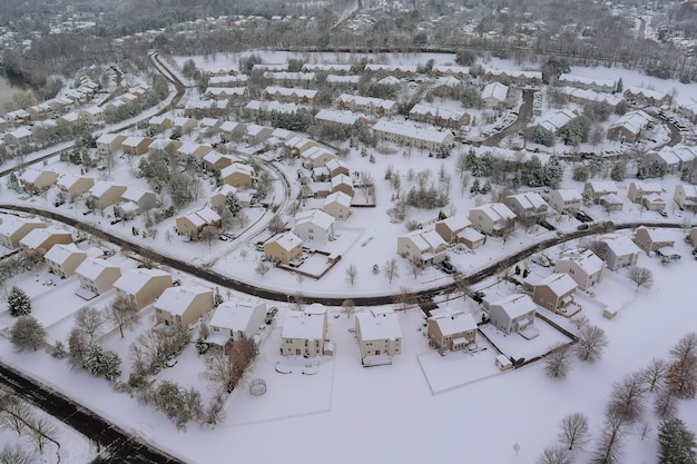 A vista aérea de inverno das casas no telhado dos pátios residenciais de uma pequena cidade coberta de neve