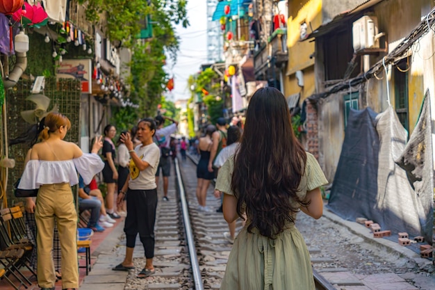 A vista de trás de uma jovem asiática posando em frente à ferrovia A vida das pessoas que vivem perto da ferrovia na cidade antiga de Hanoi A rua ao lado da linha de trem é um lugar famoso para os turistas de Honoi