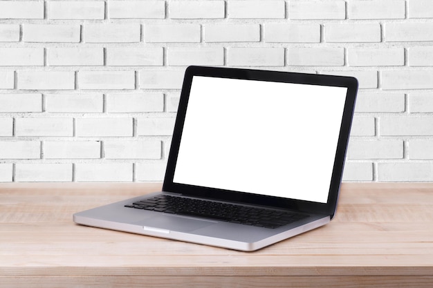 A vista frontal do laptop está na mesa de trabalho e no fundo de tijolo branco