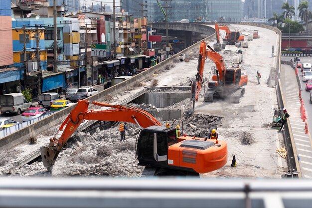 A vista na estrada da construção da estrada trabalha com máquina escavadora vermelha.