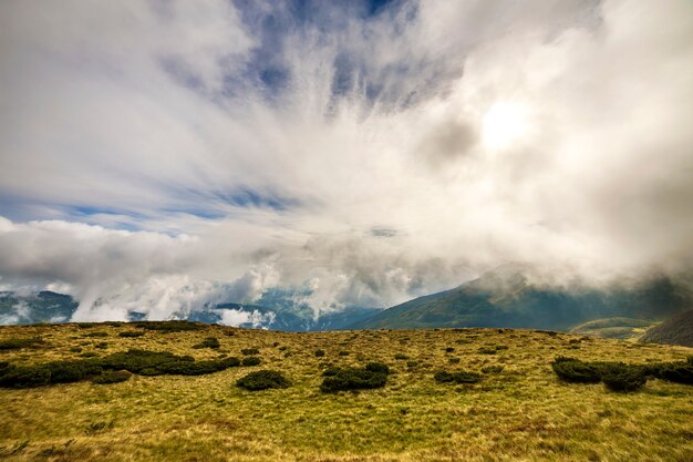 A vista panorâmica das montanhas verdes no céu azul com nuvens brancas copia o fundo do espaço no dia ensolarado brilhante. turismo e conceito de viagem.